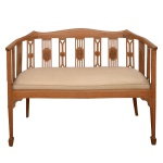 Pequeno sofá em madeira clara. Encosto construído com tabelas montadas em ripas realçadas por medalhões. Cachaço ondulado, acoplado a braços com montantes verticais rematados por pernas retas e pés salientes. Assento com almofadão estofado em tecido bege, apoiado em saia retilínea.. 80 x 101 x 40 cm.