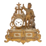 Belo relógio de mesa, provavelmente francês, ornamentado em bronze ormolu. Base retangular em mármore claro, com frente revestida por placa vazada e ornada por frisos estilizados, medalhões e pés em volutas. Apresenta estatueta de aristocrata do século XVII com cão aos pés, encostado em caixa com mostrador circular em esmalte branco, ladeada por arabesco. Parte superior ornada por composição arquitetônica com colunas caneladas, adornos florais e coroa encimada por pequena urna. (Braço direito da figura quebrado, desgastes do tempo na douração, marcas de uso). 37 x 35 x 10 cm. Necessita de reparos. Não funciona.