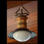 THOMSON-NY-USA - Luminária americana de teto, com bojo cilíndrico em cobre vermelho, sustentando chapéu circular preto centralizando cúpula piriforme em vidro leitoso. Parte superior com coroa dourada encimada por suporte em cruz e corrente. Fabricante: THOMSON Enclosed Arc Lamp - Electric Co. Completo. Possui o suporte da parte de cima original. 55 x 40 cm.