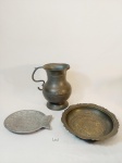 LOTE COM 3 PEÇAS SENDO 1 JARRA PARA ÁGUA/SUCO EM ESTANHO COM AVARIAS MASSADO, E DESGATE, 1 PRATO DECORATIVO COM BORDAS TRABALHADAS EM ESTANHO E 1 PETISQUEIRA EM FORMATO DE PEIXE EM ALUMÍNIO. MEDIDA: JARRA 12,5 CM D, TRAVESSA 20,5 CM D, PETISQUEIRA 17 CM X 12,5 CM DE LARGURA
