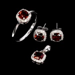 Elegante conjunto composto por um par de brincos, anel e pingente ambos em prata de lei espessurada a ouro branco. Design moderno exclusivo com preciosa Granada Rodolita de 5.0 mm, clássica lapidação almofada brilhante, adornadas por rico e fino acabamento com bela coroa de Zirconias extra brancas. Conjunto em perfeito estado de conservação, sem uso. Par de brincos 0,7 cm , aro do anel 1,7 cm , pingente 1,3 x 0,7 cm. Origem Moçambique.