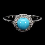 Belíssimo anel em prata de lei espessurada a ouro branco, design exclusivo de excepcional ourivesaria com linda Turquesa azul extra de 6.0 mm, clássica lapidação cabochon, adornada por rico trabalho e fino acabamento com elegante coroa de Zirconias extra brancas. Perfeito estado de conservação, sem uso. Aro mede 1,8 cm. Origem Brasil.