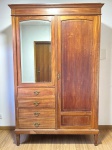 MOBILIÁRIO - Armário guarda-roupa estilo anos 50 composto 4 gavetas com puxadores em metal dourado. Duas portas, sendo uma com espelho bisotado externo. Interior com travessão para cabides. Em Peróba do Campo, filetada. Med. 220x146x60 cm. Chave amassada.