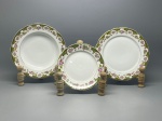 PORCELANA - Parte de jogo de jantar em porcelana branca com borda levemente recortada, fina decoração com detalhes em verde, arabescos, filetagem a ouro, flores policromadas. Composta de: 10 pratos de sobremesa, 12 pratos rasos e 12 pratos fundos. Maior 23 cm e menor 18 cm. Leves bicados.