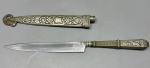 METAL - CORNETA - Antiga faca gaucha em metal espessurado a prata de manufatura Eberle - Corneta ricamente adornada por motivos florais; lâmina lisa, somente a marca do fabricante. Peça em perfeito estado de conservação.Med. 23 cm.