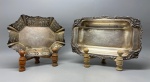 METAL - Lote de antigas travessas em metal espessurados a prata, sendo 1 Meridional, com belo trabalho de cinzelamento nas bordas e 1 travessa com borda delicadamente vazada. Med. 32x21x5 cm e 4x16x20 cm. Marcas do tempo e de uso.