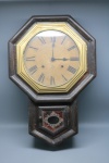 RELÓGIO - RELÓGIO DE PAREDE OITAVADO EM MADEIRA - Elegante relógio de parede de formato oitavado, com caixa em madeira de tonalidade escura e pátina que evidencia sua idade. O mostrador, em tom creme com algarismos romanos em preto, é emoldurado por um aro dourado (em material plástico). A parte inferior da caixa apresenta um detalhe decorativo com pintura e um medalhão central, adicionando um toque de charme. Ideal para compor a decoração de ambientes clássicos, rústicos ou com temática vintage, este relógio combina funcionalidade e valor estético.. Med. 52x38x12 cm. Não testado e sem garantia. No estado.