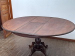 MOBILIÁRIO - MESA REDONDA ANTIGA EM MADEIRA MACIÇA COM BASE PEDESTAL - Elegante e robusta mesa redonda de época, confeccionada em madeira maciça de tonalidade escura, ideal para compor ambientes que buscam um toque de classicismo e funcionalidade. Seu tampo, com 120 cm de diâmetro, é sustentado por uma imponente base central tipo pedestal, ricamente torneada e com pés curvados, garantindo estabilidade e um visual sofisticado. Com 80 cm de altura, esta mesa é perfeita para refeições em família, encontros sociais ou como peça central em um hall de entrada. A pátina natural da madeira atesta sua autenticidade e história.Med. 80x120x157 cm. Marcas do tempo. Observação importante: A peça apresenta um antigo ataque de broca na parte inferior do tampo, que já foi tratado e não compromete a estrutura ou a beleza da superfície superior.