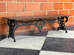 MOBILIÁRIO - BANCO DE JARDIM EM FERRO FUNDIDO E MADEIRA - Elegante banco de jardim com estrutura em ferro fundido ricamente ornamentado e assento em tábuas de madeira natural. As laterais e o suporte central em ferro fundido apresentam um desenho clássico de arabescos e volutas, remetendo ao estilo vitoriano e tradicional. Ideal para compor áreas externas como jardins, varandas e pátios, ou como um elemento de destaque em ambientes internos que buscam um toque de robustez e sofisticação antiga. Peça de época, em excelente estado de conservação, com a pátina natural do ferro e da madeira que conferem autenticidade e charme. Med. 44x160x39 cm.