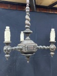 ILUMINAÇÃO - LUSTRE ANTIGO EM MADEIRA ENTALHADA ESTILO MANOELINO - Imponente lustre de teto, uma peça de rara beleza que evoca a grandiosidade e a riqueza de detalhes do estilo Manoelino. Confeccionado em madeira escura, o lustre apresenta uma estrutura robusta com três braços retos ricamente entalhados e adornados com detalhes ornamentais em relevo. O corpo central e a coluna superior destacam-se pelos seus trabalhos entalhados, incluindo uma notável coluna canelada em espiral. Os suportes para as lâmpadas possuem um charmoso formato de vela com efeito de cera derretida. Perfeito para adicionar um toque de elegância, história e autenticidade de época a salas de jantar, halls de entrada ou ambientes que buscam uma iluminação com personalidade e caráter. A peça necessita de revisão elétrica para pleno funcionamento. Med. 86x53 cm.