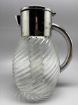 DEMI CRISTAL - Jarra  em demi cristal, translucido, incolor e retorcido, com bocal e alça em metal espessurado a prata. Alt. 26 cm.