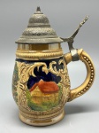 FAIANÇA - Tankard em faiança alemã vitrificada com decoração típica da região com tampa em pewter cinzelada. Alt. 17 cm. Trincado.