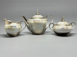 PORCELANA - Conjunto de 3 peças, jogo de chá em porcalana branca com decoração furta cor e faixa prateada. Composto de: Bule (com pegador colado), leiteira e açucareiro. Maior 17 cm e menor 11 cm.