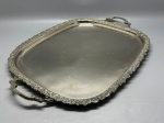 METAL - Bela bandeja em metal espessurado a níquel contendo borda e alças cinzeladas por decoração floral e cachos de uvas. Med. 59x49x42 cm.