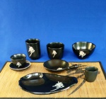 KENZO TAKADA -  Interessante conjunto de serviço para culinária japonesa, com exclusivo design do famoso estilista e perfumista japonês.  Em cerâmica negra e assinatura do ideograma da marca, é composto por 09 peças, sendo: esteira em bambu, prato de apoio em poliestireno negro e 07 peças em cerâmica. Bowls, pratinho e vasos pequenos. Maior peça mede 9 x 7 cm.