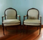 MOBILIÁRIO - Belo par de cadeiras em madeira maciça, com braços  estofados, ricamente entalhadas. Estofadas em tecido listrado, tachado ao estilo francês. Medem 88 x 60 x 48 cm. Apresentam marcas de uso.