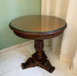 COLONIAL - Tradicional mesa auxiliar redonda em madeira de lei, com detalhes entalhados na coluna central e saia. Acompanha tampo de vidro. Mede: Altura - 58 cm ediâmetro - 57 cm.