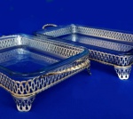 PRATA - Dois antigos berços para refratários, em metal espessurados a prata, com corpo vazado, pés em curva e alças. Acompanhas duas peças refratárias. A maior mede 5 x 23 x 40 cm; a menor mede 5 x 20 x 35 cm.