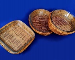SERVIÇO DE MESA - Conjunto com três travessas refratárias, duas ovais e uma quadrada, decoradas com suportes em rattan natural. Marcas de uso. Medem 7 x 28 x 40 cm e 7 22 x 22 cm. Mínimos bicados.