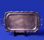 PRATA - Importante bandeja em metal espessurado a prata, antiga peça decorada com florões cinzelados ao fundo, bordas e alças em relevo. Mede 24 x 42 cm.