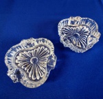 CRISTAL - Par de singelos cinzeiros em grosso cristal, em formato similar a corações, em delicado trabalho bisotado. medem 2 x 8 x 8 cm.