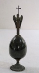 Arte Sacra Russa ao gosto Faberge no formato de ovo , em pedra no tom verde, topo com uma escultura de anjo com uma cruz em bronze. Med. 17 cm alt.