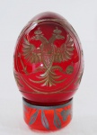 Ovo decorativo ao gosto Fabergé em cristal russo em tom rubi, lavrado com cabeças de Fênix , verso com coroa e espadas realçados a ouro. Marcado na base com o símbolo e logomarca da empresa Russa . Acompanha base. Med. 12 cm alt.