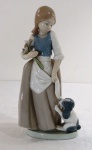 NAO by LLADRO- Escultura em fina porcelana espanhola, com marca da manufatura, representando "Menina com flor e cão" em rica policromia. Marcado e datado na base  Daisa 1986. Med. 23,5 cm alt.