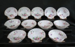 Doze (12) petisqueiras em porcelana japonesa na cor branca vitrificada, em formato de concha, decorada com flores e filetes dourados. Medidas; 10 cm diâmetro. Marcado no fundo.