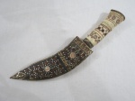 Uma (1) antiga JAMBIYA (punhal ou adaga, tradicional da península árabe, símbolo de status, honra e masculinidade, rito de passagem dos meninos para idade adulta, marcando sua inclusão nas estruturas tribais e sociais), lâmina em aço , bainha em chifre com estrutura em metal ricamente decorado, cabo osso/marfim. Sinais de uso na lâmina. Med. 33 cm comprimento.