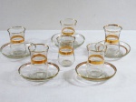 Seis (06) copos para aperitivo e cinco pires em vidro translúcido decorados com frisos dourados. Med. 8 cm alt.