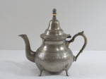 ARGENT- Bule para chá em metal espessurado a prata, base sob quatro pés em concha, bojo cinzelado, tampa retrátil com isolante térmico na cor marfim. Md. 21 cm alt.