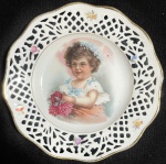 BAVARIA (Schumann) - Antigo e raro prato alemão, Art Nouveau, séc XIX, em porcelana na cor branca, Bavária, com borda vazada, finamente policromado, realçado a ouro, decorado por Cena de Menina e Flores. Marcado na base. Med 19 cm.
