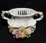 BASANO - Belíssima e antiga ânfora italiana, ao gosto barroco, anos 50, em porcelana, ricamente entalhado e policromada, com borra vasada, decorada por Flores em relevo. Apoiada sobre 4 pés representando Garras. Med 16x24 cm.