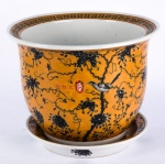Cachepot com o seu respectivo presentoi'r em porcelana oriental. Esmaltagem em tom amarelo decorado com "Paisagem e Pássaros" em tom negro. Assinado com ideogramas e selo vermelho. Fundo do cachepot com furo. Med: 27,5x20,5 cachepol /3x23prato/cm.