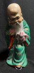 ARTE ORIENTAL - "Shou Xing" Imponente e antiga escultura chinesas, ao gosto dinastia Ching, anos 50, em porcelana finamente esmaltada a mão realçada a ouro, representando Cena de Deus da Longevidade Com Criança. Med 22 cm. Obs: Apresenta lascado. As representações artísticas geralmente retratam Shouxing como um velho barbudo, com sobrancelhas altas e um cajado torto em uma das mãos. Ele segura o pêssego da imortalidade na outra mão. Uma cegonha ou tartaruga é frequentemente acrescentada como mais um símbolo de longevidade, que os chineses consideram uma bênção especial.
