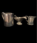 Três elegante e antigas peças Arte Deco, anos 50, em metal ricamente cinzelado, sendo 1 molheira, 1 cremeira e uma jarra. Med:11 x14 x 18 / 17,5 x 8 x 10 /9,5 x 11,8 x 6 cm.