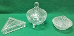 Lote com  três peças em  de vidro, sendo que da esquerda para direita, porta jóias de demi cristal em forma  triangular com decoração em formas geométricas; bomboniere em vidro,  com pés delicados e um padrão floral; da direita, pote em vidro arredondado, decorado com formas geométricas. Usados. Sem trincas, quebras ou trincados.