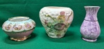 Lote com 3 peças em procelana e cerâmica sendo que o da esquerda trata-se de um pote com  formato arredondado, base e borda douradas e ricamente decorado com cenas galantes; o vaso do meio é branco, com uma textura em alto-relevo e delicadas flores pintadas e o da direita um vaso para flores, pintado em  um padrão marmorizado em tons de roxo e um anel preto no pescoço. Usados. Todos em muito bom estado.