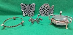 lote com 5 peças em metal, sendo que da esquerda para a direita temos; base em metal para cinzeiro, com bordas decoradas e três pequenos pés,  suporte de mesa para travessas ou panelas, em metal, com  forma de borboleta com desenhos vazados intrincados; outro suporte de mesa para travessas ou panelas, em metal, com  forma de peixe,  com desenhos vazados; suporte para cinzeiro com  quatro pernas em forma de dragão; espiriteita de acampamento antigo. Usados. Todos em muito bom estado.