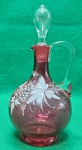 Azeiteira antiga, executada em vidro soprado, diáfano, tonalidade rosa, decorada com flores em esmalte, bojo globular seguido de gargalo tubular, boca ondulada e revirada pra cima, tampa ovoide, alça lateral curvada