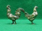 Par de esculturas em metal prateado, representando galo e galinha. Cada peça mede 7cmA X 2cmL X 6cmC.