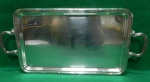 Pequena bandeja de metal, banhada à prata, com bordas e alças decoradas no padrão fita cruzada. 44cmC x 21cmL. Sem marca aparente Usado.