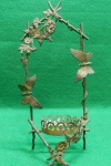 Antigo e pequeno suporte para vasos solitários, confeccionado em cobre e ricamente decorado com motivos florais e borboletas. Peça muito delicada e antiga. Patina provocada pela ação do tempo. Usado. Em muito bom estado. Mede 26 A x 12 C x 7 L.