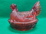 Pote de vidro "Galinha no Ninho", na cor vermelha. Apresenta restauro e dois pequenos lascados na borda da base, tudo como pode ser visto nas fotos. Usado. 16 A x 19 C x 14 L