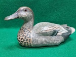 Chamariz (isca) de pato flutuante, sendo que esse representa um " pato trombeteiro". Confeccionado em madeiro e esculpido e pintado à mão. Década de 70. Usado. Muito pouco desgaste da pintura. Mede 10 A x 21 C x 8 L.