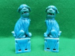 Par de esculturas em porcelana, representando "Cães de Fó", figuras mitológicas chinesas. Medem 11,5 A x 3,5 c x 4,5 L . Um deles apresenta marca de restauro entre o cão e a base, quase imperceptível.