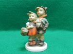 Pequeno bibelo em porcelana, Hummel, "Surprise".  Fabricado por Goebel Porzellan. Origem Alemanha. Apresenta perda da alça da cesta e lascado na ponta do cabelo da menina. Usado. Mede 10,5 A x 7 C x 4,5 L.