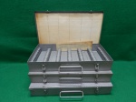 lote com 3 porta slides, em metal com pintura esmaltada. Cada uma tem capacidade para armazenar 150 slides. Aparenta nunca ter em sido usados. mede  5 A x 37 C x 19 L.