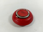 CINZEIRO - BOLSO: Antigo cinzeiro de bolso em ferro forrado em couro na tonalidade vermelho, no formato redondo. Medidas: altura: 2 cm e diâmetro: 6 cm.